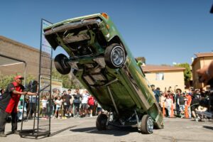 Dynamic scene of a lowrider car performing a stunt in an urban street event.